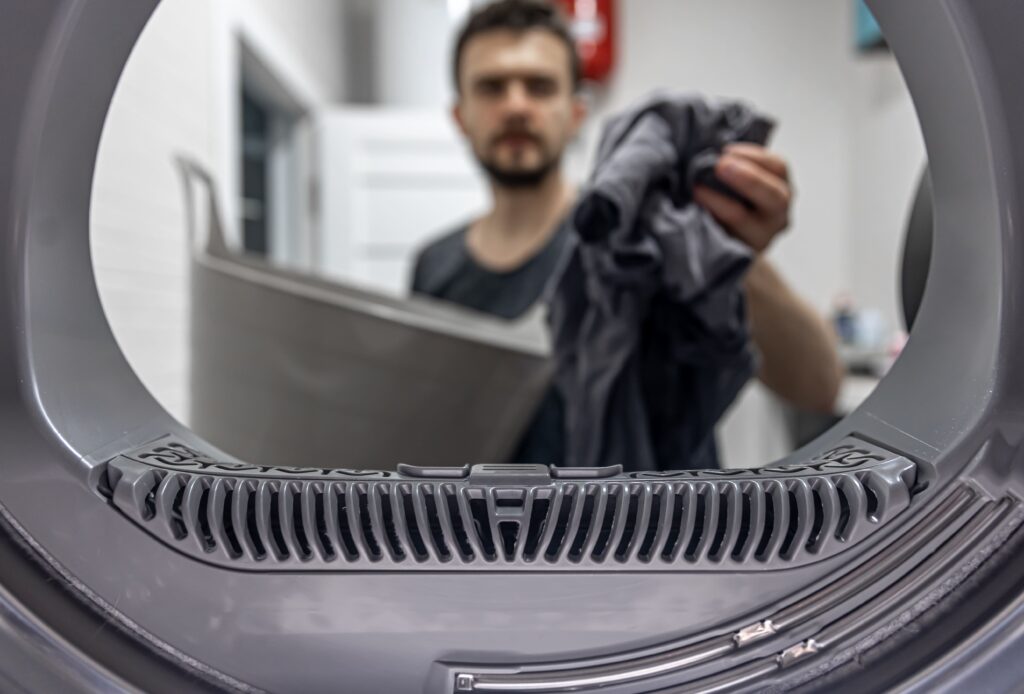 man-holding-dirty-cloth-hand-view-inside-washing-machine